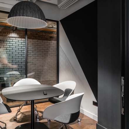 Modern office space rental at Konstruktorska 11, Warsaw Mokotow, featuring a small meeting area with stylish chairs and a round table.
