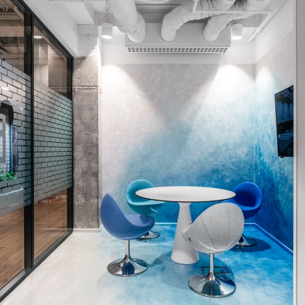 Modern office space rental at Konstruktorska 11, Warsaw Mokotow, featuring a stylish meeting area with a round table and colorful chairs.