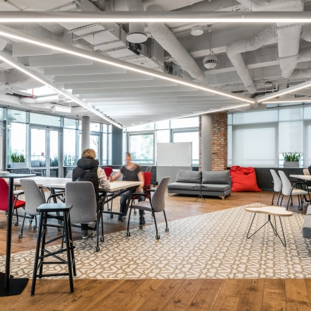 Modern office space at Konstruktorska 11 in Warsaw Mokotow with people collaborating at tables. Ideal for office space rental.