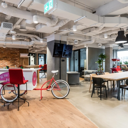 Vibrant office space at Konstruktorska 11 in Warsaw Mokotow, featuring modern furnishings, a cycle-themed bar area, and spacious seating. Ideal for office space rental.
