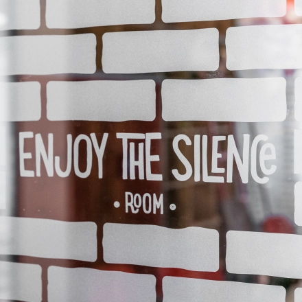 Close-up of a glass partition with brick pattern and 'Enjoy the Silence Room' text in an office space for rent at Konstruktorska 11, Warsaw Mokotow.