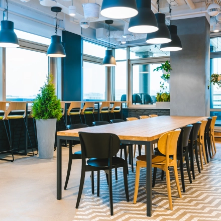 Furnished office space with a long wooden table and chairs, situated in Warsaw Mokotow. Ideal for office space rental with natural lighting and modern decor.