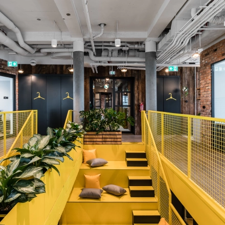 Bright and modern office to rent at Konstruktorska 11 in Warsaw Mokotow, featuring yellow accents, greenery, and an inviting work environment.