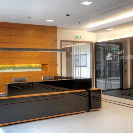 Spacious reception area at Postępu 17A, Warsaw Mokotow, ideal for office space rental, featuring a modern wooden desk and sleek decor.