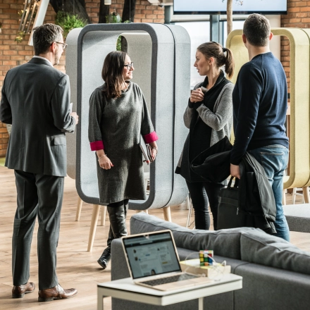 People engaging in conversation in a modern, furnished workspace, showcasing office space rental options at Al. Jerozolimskie 181B in Warsaw Ochota.