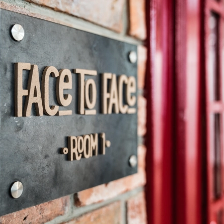 Close-up of a sign reading 'Face to Face Room 1' on a brick wall at the office to rent on Al. Jerozolimskie 181B, Warsaw Ochota.
