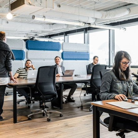 Modern office space with people working on laptops at desks, located in Warsaw Ochota, perfect for office space rental.