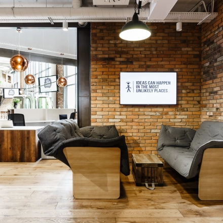Cozy office space with modern furniture, exposed brick walls, and a shared seating area at Al. Jerozolimskie 181B, Warsaw Ochota. Ideal for office space rental.