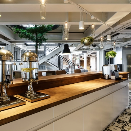 Stylish office space with modern decor in Warsaw Ochota; features a coffee station and lounge area, ideal for business meetings or as an open workspace.