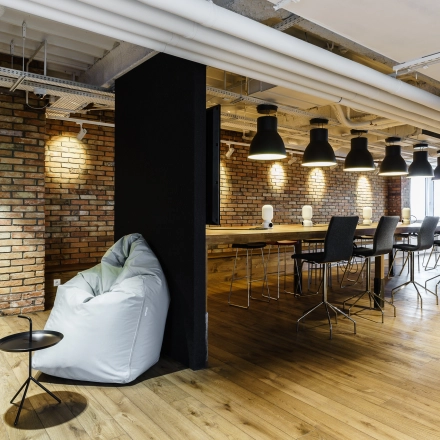 Modern office space with brick walls, wooden flooring, high ceilings, and a mix of seating options, perfect for open-floor plan office space rental.