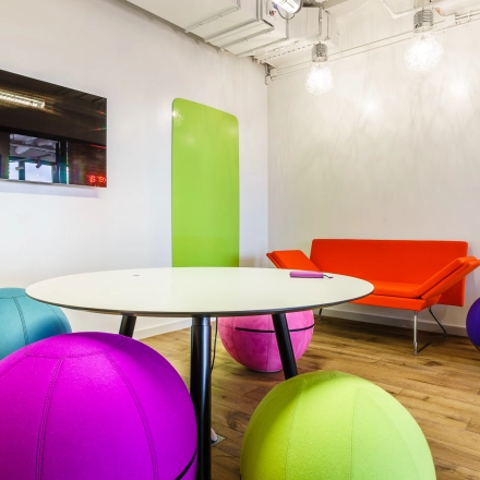 Bright and colorful office space with a round table and vibrant seating, part of an office to rent in Warsaw Ochota.