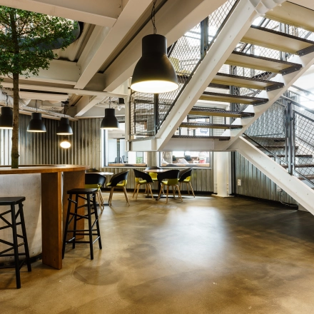 Modern office space with high ceilings and open floorplan at Al. Jerozolimskie 181B, Warsaw Ochota. A person is casually walking up the stairs.