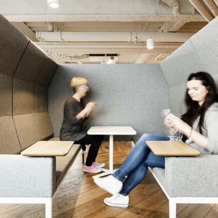 Two individuals are engaged in discussion in a cozy, modern meeting pod in an office available for rent at Al. Jerozolimskie 181B, Warsaw Ochota.