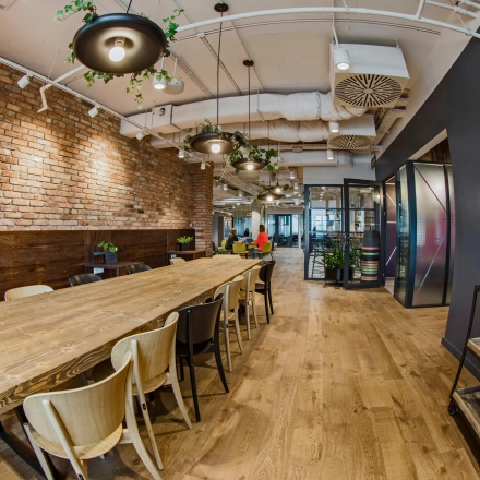 Inviting office space with a long wooden table and brick accent walls, perfect for collaborative work at Al. Jerozolimskie 181B, ideal for office space rental in Warsaw Ochota.