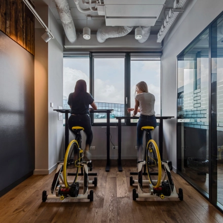 Two people engage in brainstorming while cycling at a standing desk in an office space rental at Al. Jerozolimskie 181B, Warsaw Ochota.