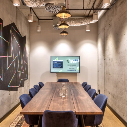 Modern conference room at Koszykowa 61, Warsaw Śródmieście, featuring a large wooden table with blue chairs, ideal for office space rental.