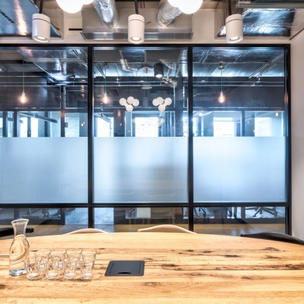 Modern office space at Koszykowa 61, Warsaw Śródmieście, featuring a wooden table and glass partition, ideal for office space rental.