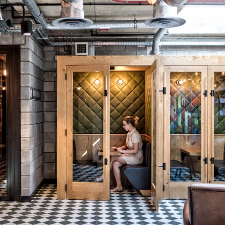 A person works on a laptop inside a cozy, wooden-paneled office space at Koszykowa 61, ideal for those seeking office space rental in Warsaw Śródmieście.