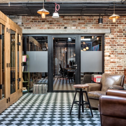 Furnished office space at Koszykowa 61 in Warsaw Śródmieście featuring cozy chairs, patterned flooring, and modern decor with ample space for meetings.