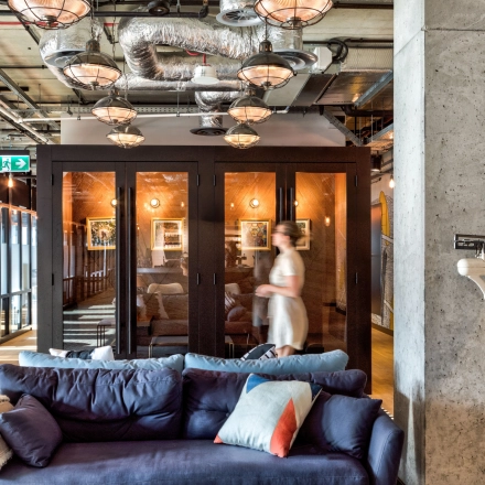 Stylish office space with modern industrial design, featuring comfortable seating and glass-walled meeting rooms at Koszykowa 61 in Warsaw, ideal for office space rental.
