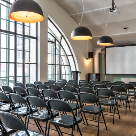 Spacious office to rent at Koszykowa 61, Warsaw Śródmieście, featuring a furnished conference room with rows of folding chairs and a large projection screen.