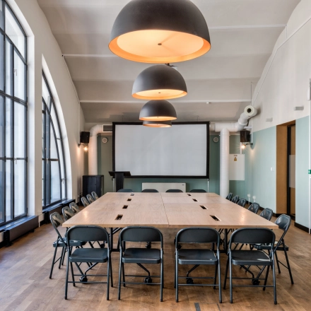 Spacious conference room available for office space rental at Koszykowa 61, Warsaw Śródmieście. Elegant lighting and a large table set-up create a professional environment for meetings and discussions.