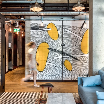 Furnished office space at Koszykowa 65 in Warsaw Śródmieście with modern decor and a casual seating area. A person is walking by, suggesting an active business environment.