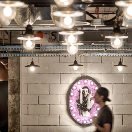 Modern office space at Koszykowa 65 in Warsaw Śródmieście, featuring ambient lighting and a unique wall decoration. A person is seen walking through the area.