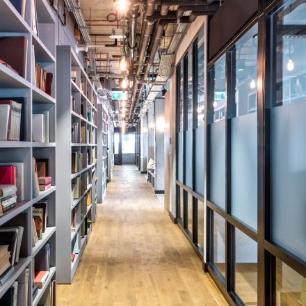 A sleek office interior at Koszykowa 65, Warsaw Śródmieście with modern book shelves lining the hallway. Perfect for office space rental.