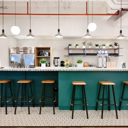 Modern office space rental in Warsaw Śródmieście with a stylish kitchenette, featuring a long counter and bar stools, suitable for quick breaks.