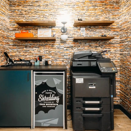 Furnished office space for rent featuring a printer and storage cabinet against a patterned wall, ideal for office space rental.