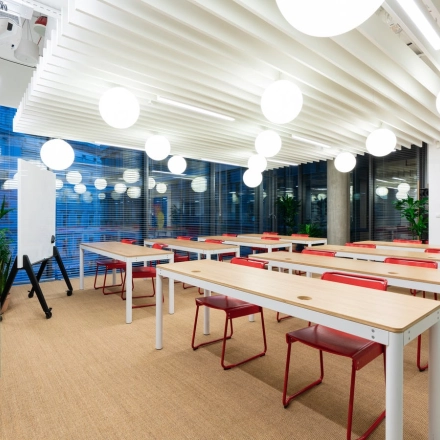Spacious, modern office interior at Krucza 50, Warsaw Śródmieście, featuring long tables and red chairs, perfect for office space rental.