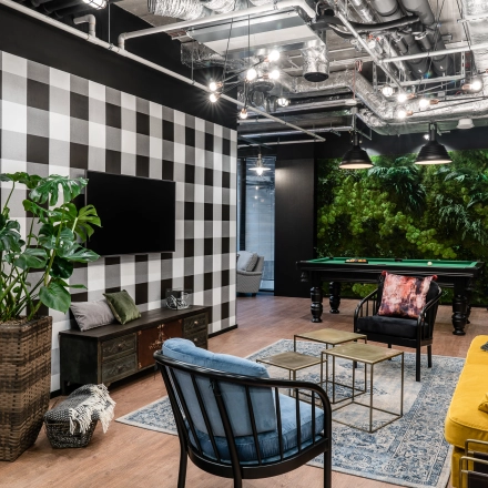 Stylish office space in Warsaw Śródmieście featuring cozy seating, a checkerboard wall, and a pool table, ideal for office space rental.