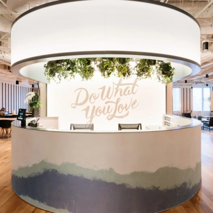 Modern office space rental at Grzybowska 60, Warsaw Wola featuring a circular reception desk with greenery and motivational signage.