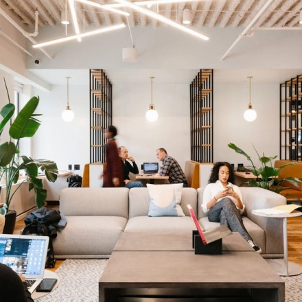 Modern office space at Grzybowska 60 in Warsaw Wola, featuring a comfortable lounge with people engaged in business tasks. Ideal for anyone looking to rent office space.