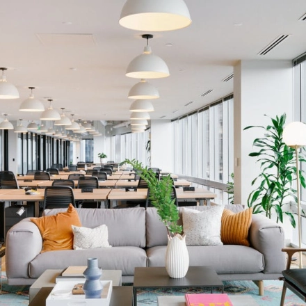 Modern, furnished office space in Warsaw Wola with rows of desks, ergonomic chairs, and a cozy seating area, available for rent at Rondo Daszyńskiego 2.