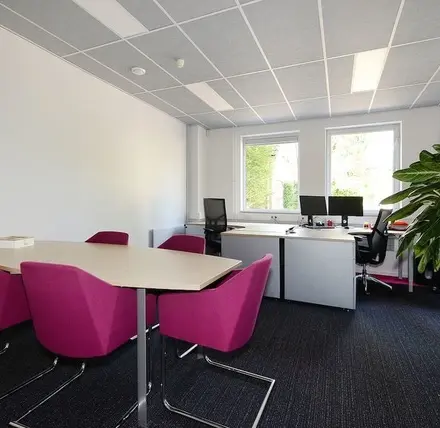 Bright office space at Molenweer 2, Wateringen, featuring modern desks, vibrant chairs, and large windows. Ideal for those seeking office space rental with natural light.