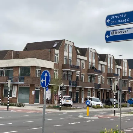 Exterior view of office building for rent at Boerendijk 8, Woerden, showing multiple levels with brick facade and parking area.