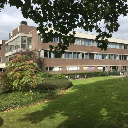 Exterior view of an office building at Houttuinlaan 4 in Woerden, surrounded by green lawns and trees, ideal for office space rental.