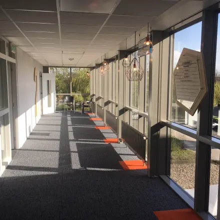 A bright hallway at Houttuinlaan 4 in Woerden, with modern lighting and large windows. Ideal for those looking to rent office space with a professional ambiance.