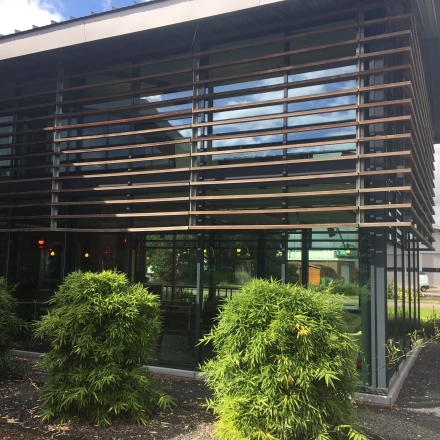 Exterior view of the office to rent at M.A. Reinaldaweg 2d in Woerden, featuring large glass windows and modern wooden slats, surrounded by greenery.