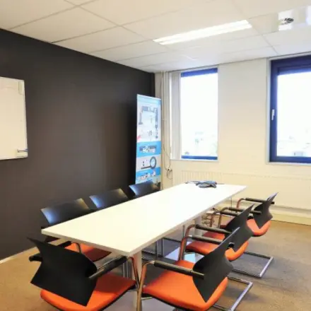 Bright office space at Pompmolenlaan 9, Woerden, featuring a meeting table and chairs near large windows, ideal for office space rental.