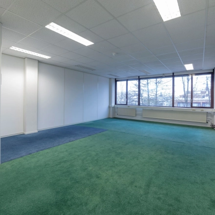 Spacious, unfurnished office space for rent at Zaagmolenlaan 4, Woerden, featuring large windows and carpeted flooring for office space rental.