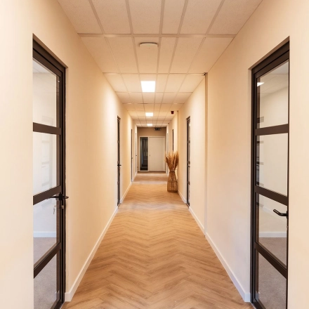 Interior hallway at Mercurion 24, Zevenaar, featuring wooden flooring and glass doors ideal for office space rental.