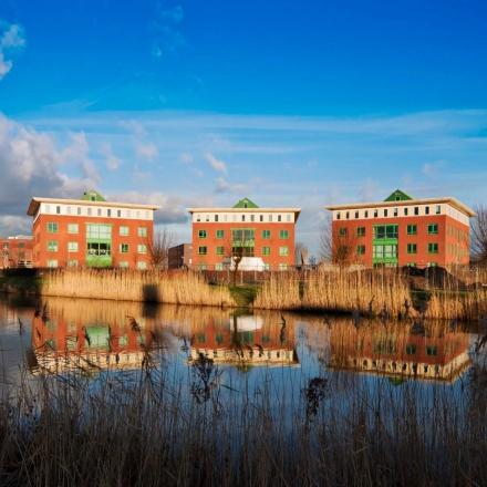 Exterior view of office buildings at Mercurion 24, Zevenaar, featuring picturesque reflections in a nearby body of water. Ideal for office space rental opportunities.