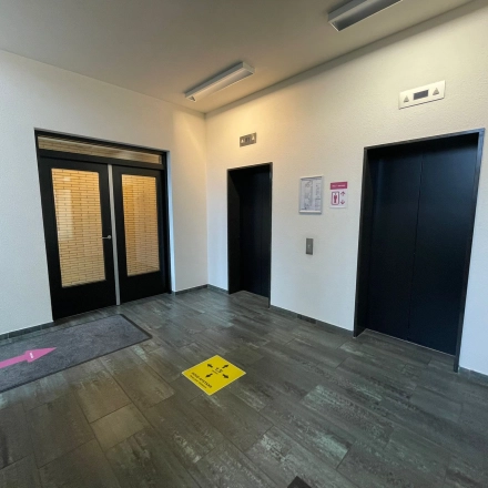 Office entrance area at Baron de Coubertinlaan 35, Zoetermeer, shown with elevators and directional signs, ideal for office space rental needs.
