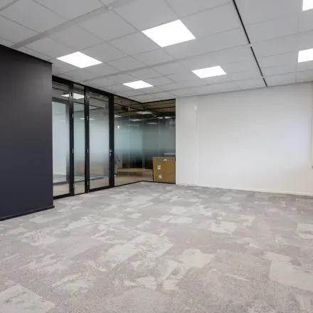 Spacious office to rent at Boerhaavelaan 40, Zoetermeer, featuring sleek glass partitions and modern ceiling lighting, ideal for setting up your professional workspace.