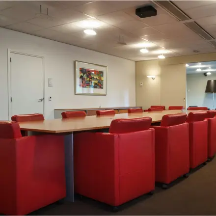 Furnished office conference room at Bredewater 26, Zoetermeer, available for rent. The room features a large table surrounded by red chairs, making it suitable for meetings.