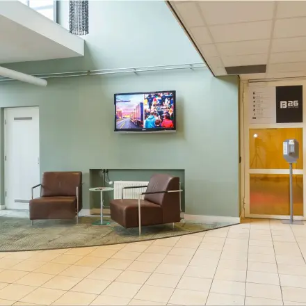 Entrance area at Bredewater 26, Zoetermeer, showing two chairs and a TV, ideal for office space rental.