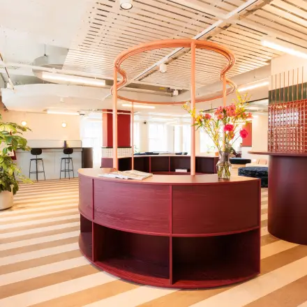 Modern furnished office space for rent at Stockerstrasse 33, Zürich Enge, featuring stylish curved furniture and vibrant decor with greenery, promoting a dynamic work environment.